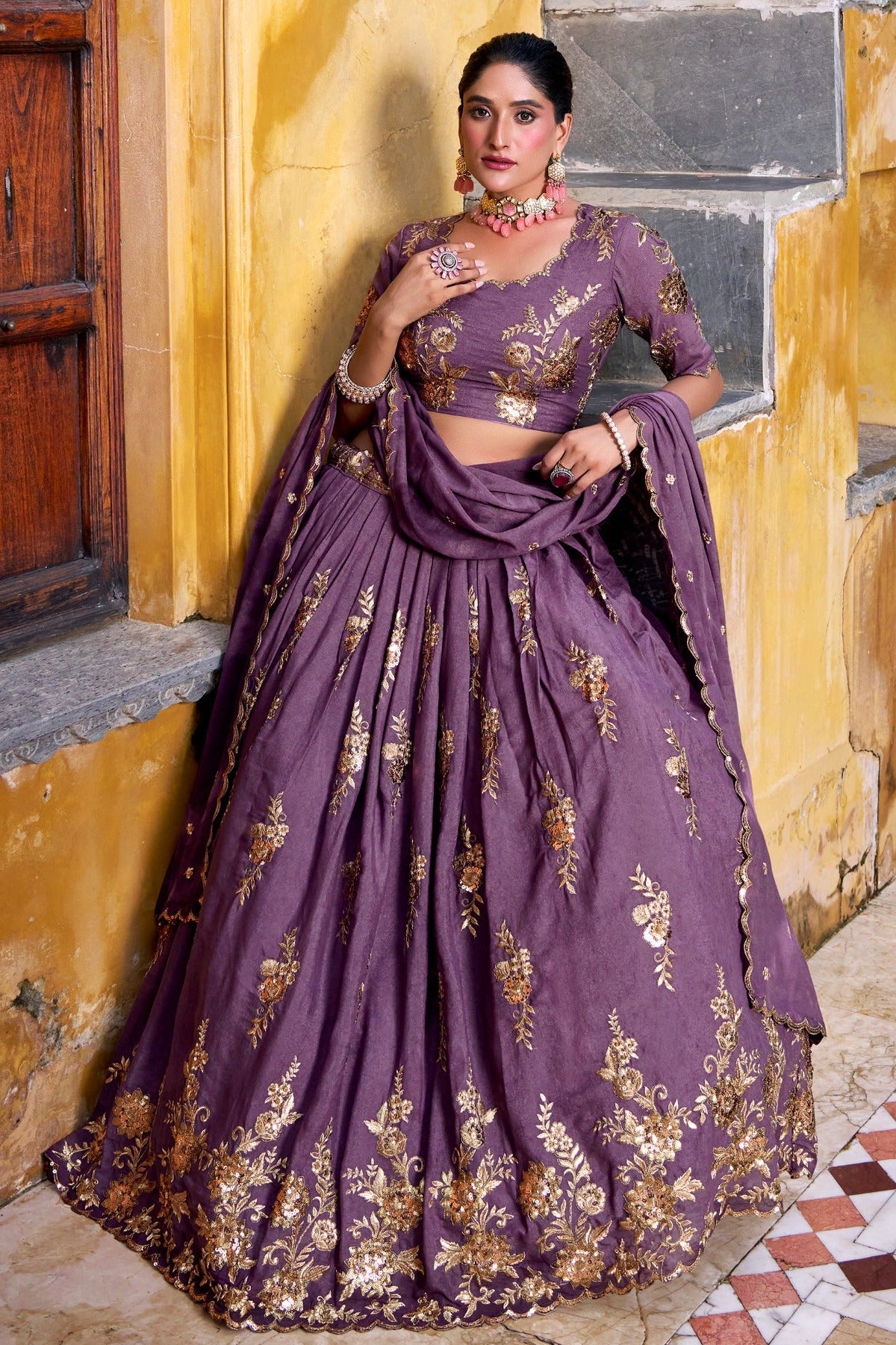 Woman in a purple traditional outfit standing on stone steps with a yellow wall background