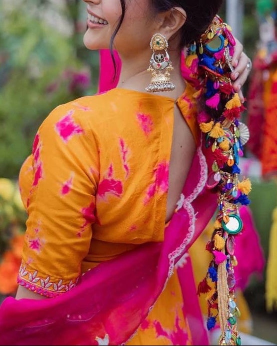 Woman in traditional attire with colorful decorations, smiling outdoors.