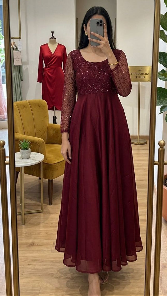 Person wearing a burgundy dress in a store setting, standing in front of a full-length mirror.