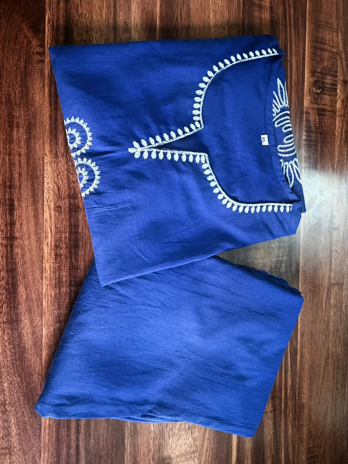 Blue garment with white embroidery on a wooden surface