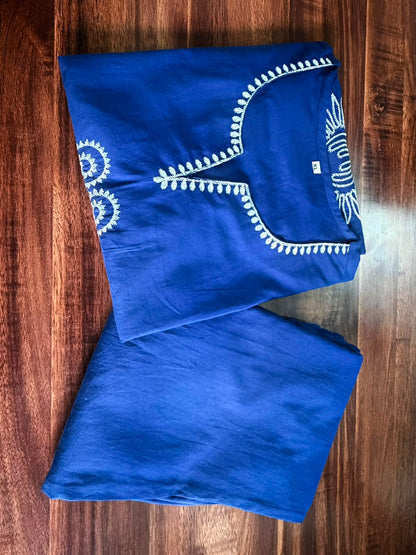 Blue garment with white embroidery on a wooden surface