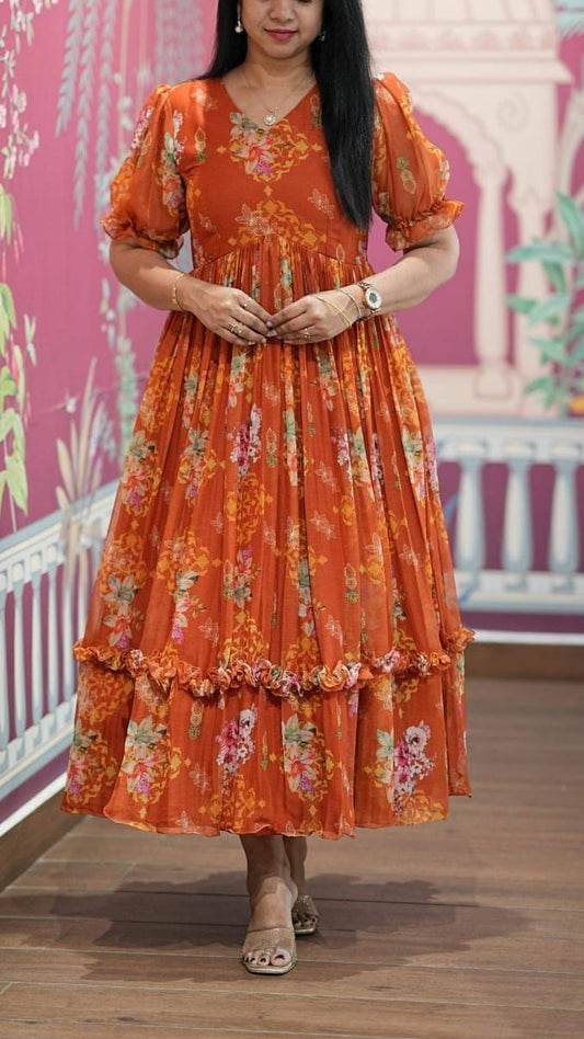 Woman wearing an orange floral dress standing in a room with decorative walls.