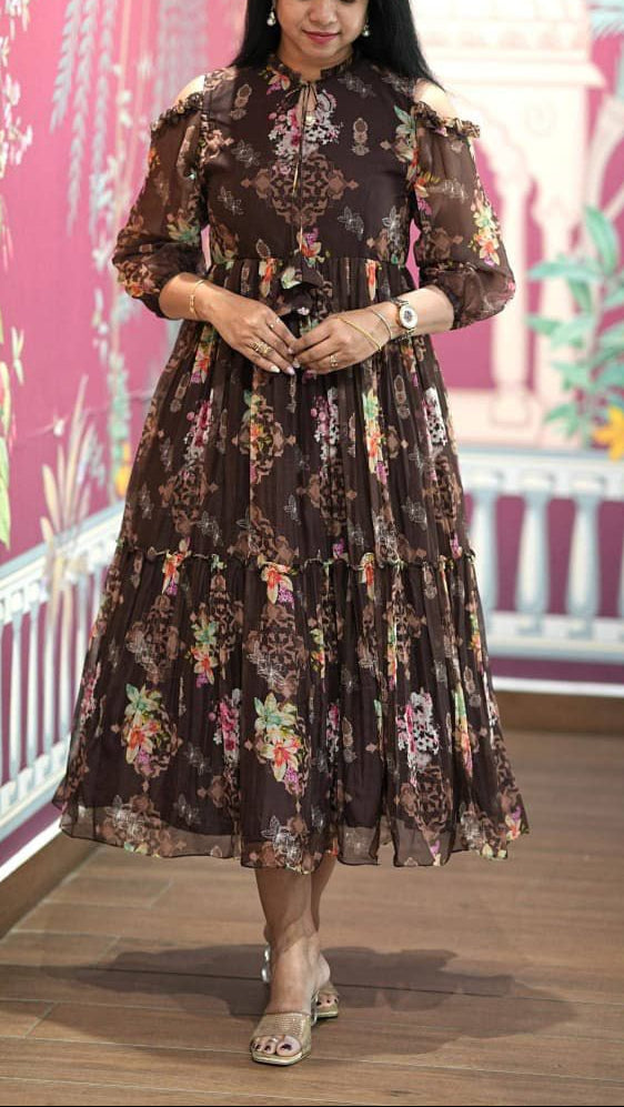 Woman wearing a floral dress standing in front of a decorative wall.