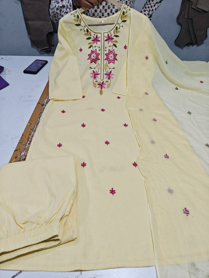 A light yellow ethnic salwar kameez suit set with matching pants and dupatta, featuring pink floral embroidery on the neckline and scattered pink motifs on the fabric.