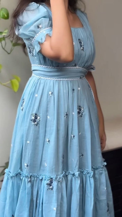 Light blue dress with floral embroidery on a neutral background