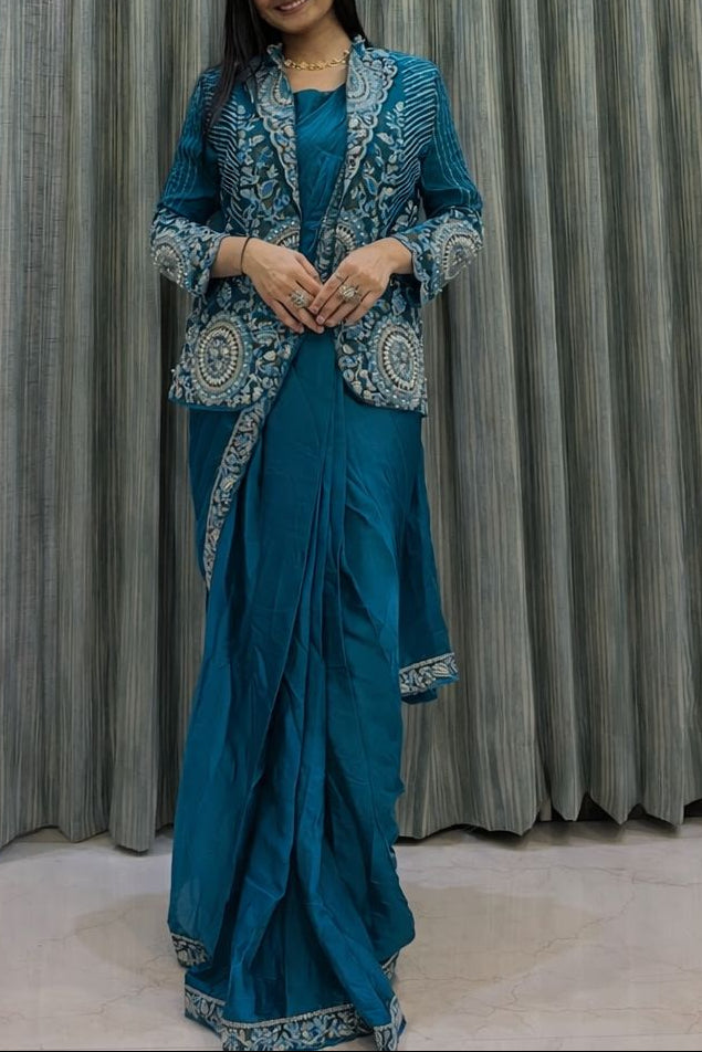 Woman in a blue traditional outfit standing in front of a textured curtain