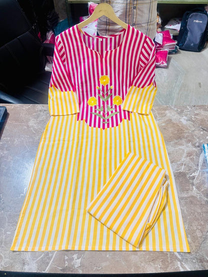 A women's kurta set with matching pants, featuring a vibrant pink and yellow vertical stripe pattern, a yellow yoke with yellow floral embroidery, and a folded pair of matching striped pants on a wooden hanger, displayed on a marble countertop.