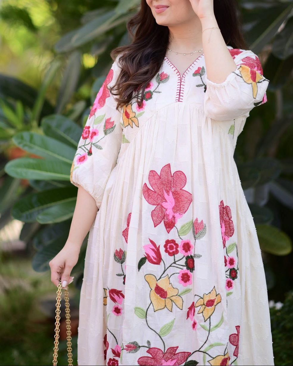 Woman wearing a floral embroidered dress in a garden setting